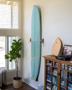 Premium oak vertical surfboard rack designed by Raili Design Co. artfully displays surfboards on any wall vertical, creating a unique coastal wall art aesthetic for surf shacks worldwide.