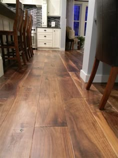 a wooden floor in a kitchen next to a dining room and living room with chairs