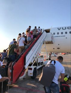 people boarding an airplane with luggage on the stairs