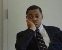 a man in a suit and tie sitting at a table with his hand on his face