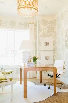 a room with a desk and chair in it, next to a wallpapered window