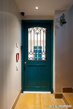 a blue door with iron bars on the top and bottom, in front of stairs