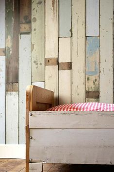 an old bed with red and white checkered pillow in front of wood paneled wall