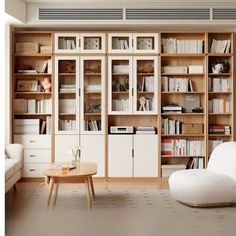 a living room filled with lots of bookshelves and furniture next to a window