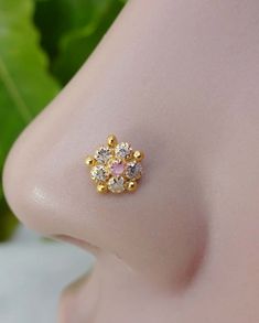 a close up view of the side of a woman's nose with gold and diamonds on it