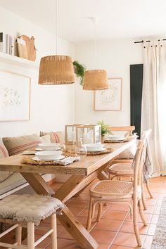 a dining room table and chairs in front of a wall with pictures hanging on it