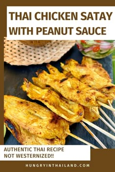 grilled chicken satay with peanut sauce on skewers, next to other food items