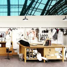 a room filled with lots of clothes hanging on the wall next to a desk and chair