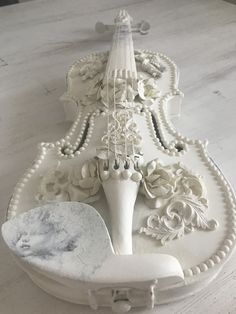 an ornately decorated white table with two spoons on it and a candle holder in the middle