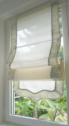 an open window with white curtains on it