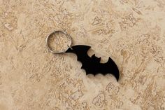 a bat shaped keychain sitting on top of a marble counter