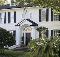 a white house with black shutters and trees