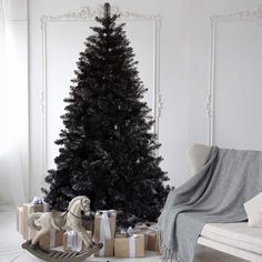 a black christmas tree with presents under it and a dog statue on the floor next to it