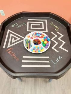 a child's drawing on a black tray with food and candy in the middle