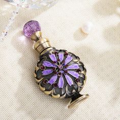 a purple and black bottle sitting on top of a table next to some glass beads