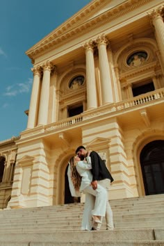 a man and woman kissing on the steps of a building