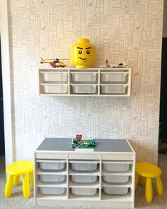 a lego table and two yellow stools in front of a wallpapered room