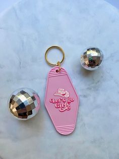 a pink keychain sitting on top of a table next to two shiny balls