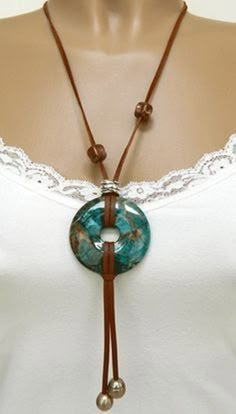 a woman wearing a white shirt and brown leather necklace with a turquoise bead on it