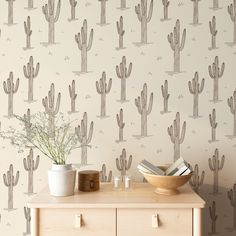 a wallpaper with cactus designs on it and two vases next to the table