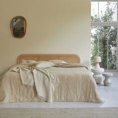 a bedroom with a bed, mirror and table next to the window in front of it