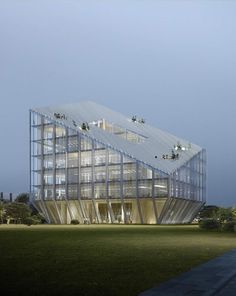 a large glass building sitting on top of a lush green field under a cloudy sky