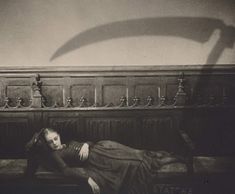 a woman laying on top of a bed next to a wall with a long shadow