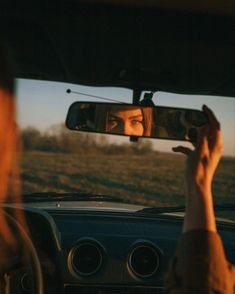 a woman taking a photo in the rear view mirror of a car with her hand up