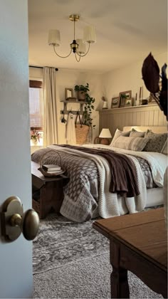 a bedroom with a large bed and two lamps hanging from the ceiling over it's headboard