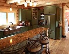 a large kitchen with green cabinets and granite counter tops, along with an island in the middle