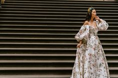 a woman in a floral dress is standing on some steps