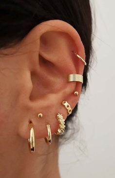 a woman wearing gold ear cuffs with different designs