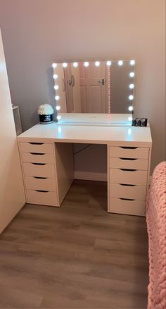 a white vanity with lights on it in a bedroom