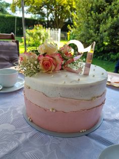 a pink and white cake sitting on top of a table next to a tea cup