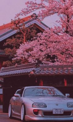 a car parked in front of a building with pink flowers on it's roof