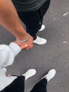 two people holding hands while standing next to each other on the street with chains around their ankles