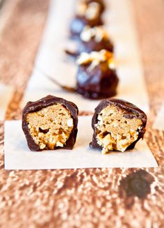 two pieces of chocolate covered dessert sitting on top of a white paper towel next to another piece of food