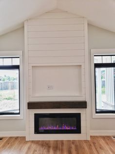 an empty room with two windows and a fireplace