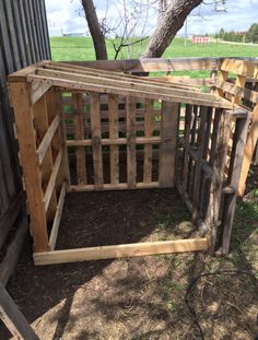 a wooden structure sitting in the middle of a yard next to a tree and fence