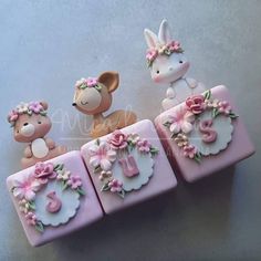 three small cakes decorated to look like animals with flowers in their ears and numbers on them