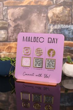 a pink and gold sign sitting on top of a wooden table next to a potted plant