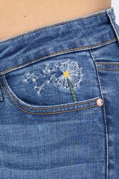 a woman's stomach with a dandelion embroidered on the back of her jeans