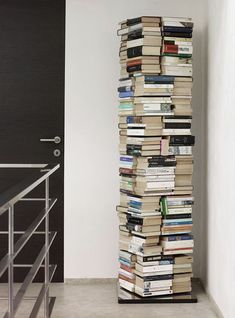 a tall stack of books sitting on top of a floor next to a stair case