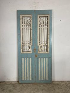 an old blue double door in a white room