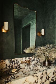 a bathroom with marble counter tops and green walls, gold fixtures and mirrors on the wall