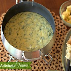 there is a pot of soup on the table with bread and crackers next to it