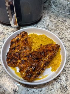 two pieces of chicken and rice on a plate next to an instant pressure cooker