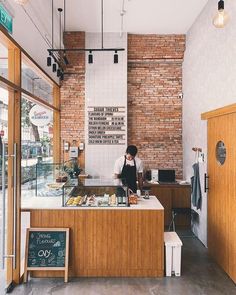 a person standing at a counter in a restaurant with brick walls and wood trimmings