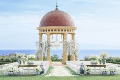 an outdoor ceremony setup with white flowers and greenery on the lawn, overlooking the ocean