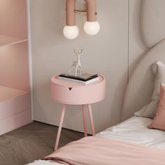 a small pink table sitting next to a bed with two lamps on top of it